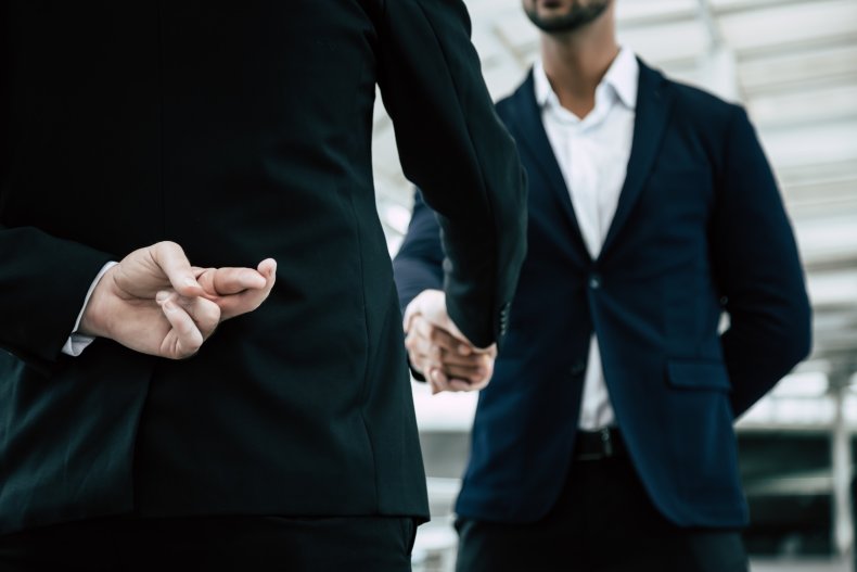 Businessman cross finger behind back during handshake
