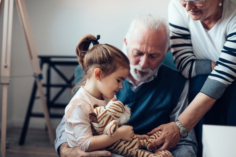 A girl holding toy, interacting with grandparents.