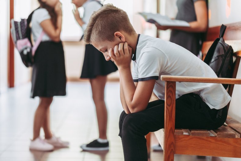 A boy sitting alone on school bench.