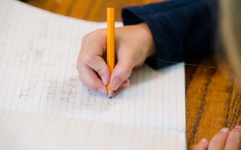 A young child writing in a book.