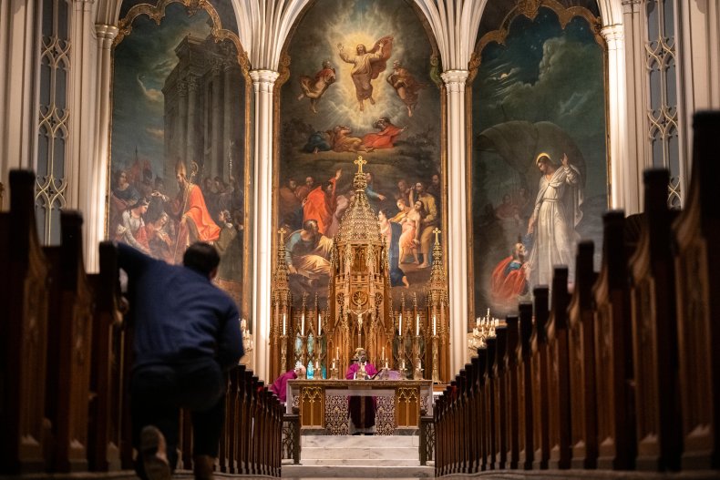 A congregant kneels in an aisle 