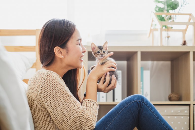 A woman playing with a tiny kitten.