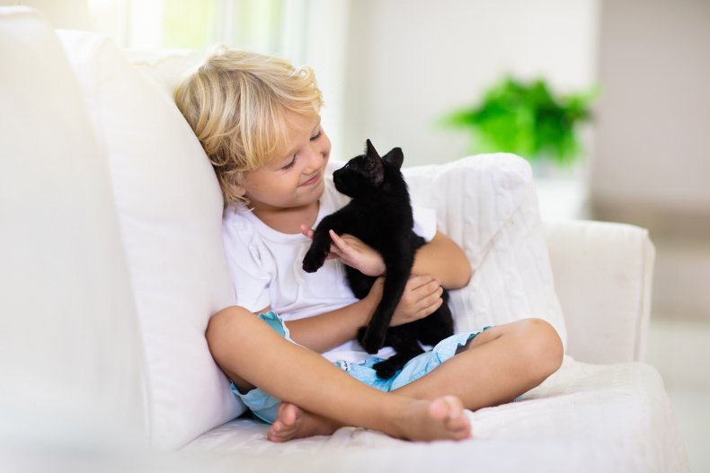 A smiling child holding a black cat. 