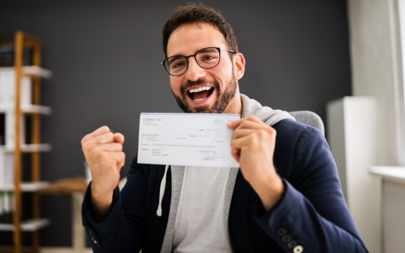 A man holding up a paycheck.