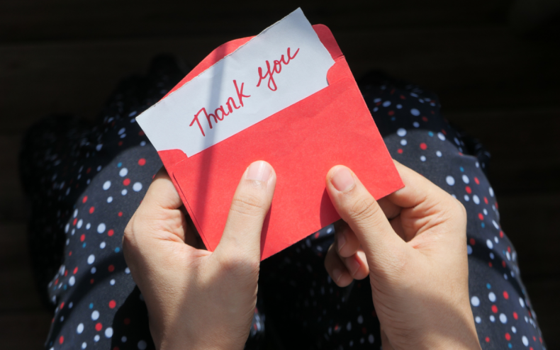 A woman opening a thank you card.