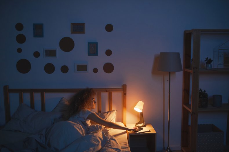A woman turning off a bedside lamp.