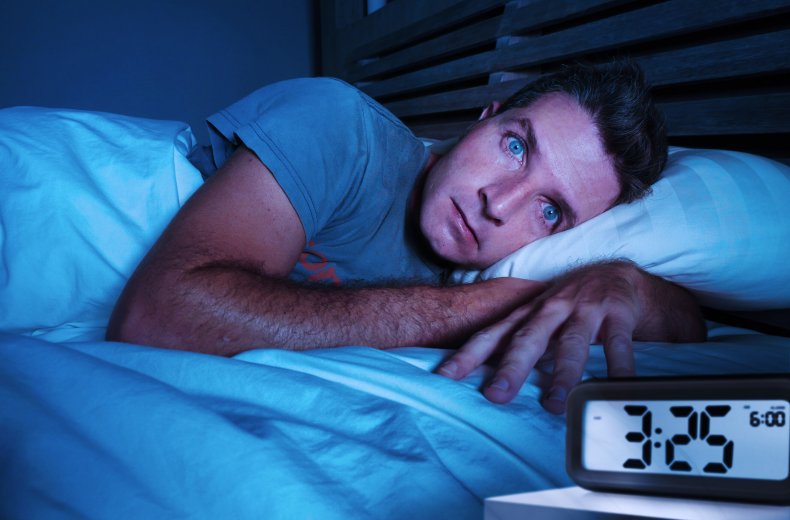 A man awake in bed at night.