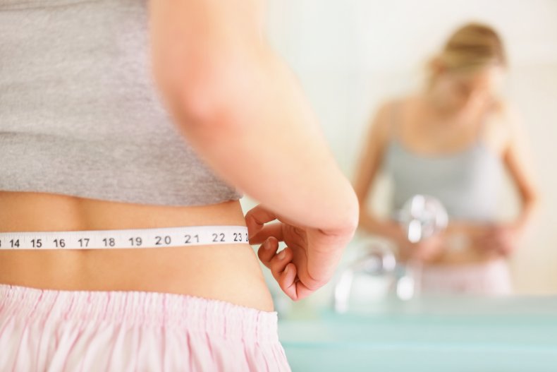 A woman measuring her waist with tape.