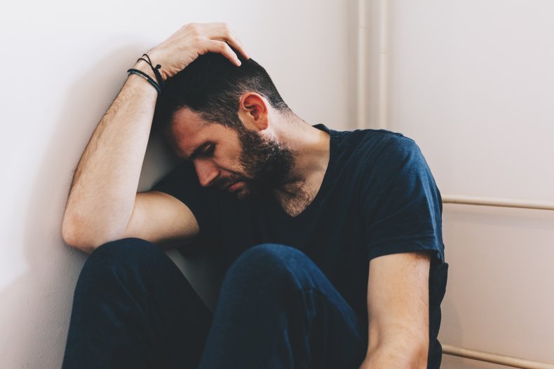 A man sitting in a corner indoors.