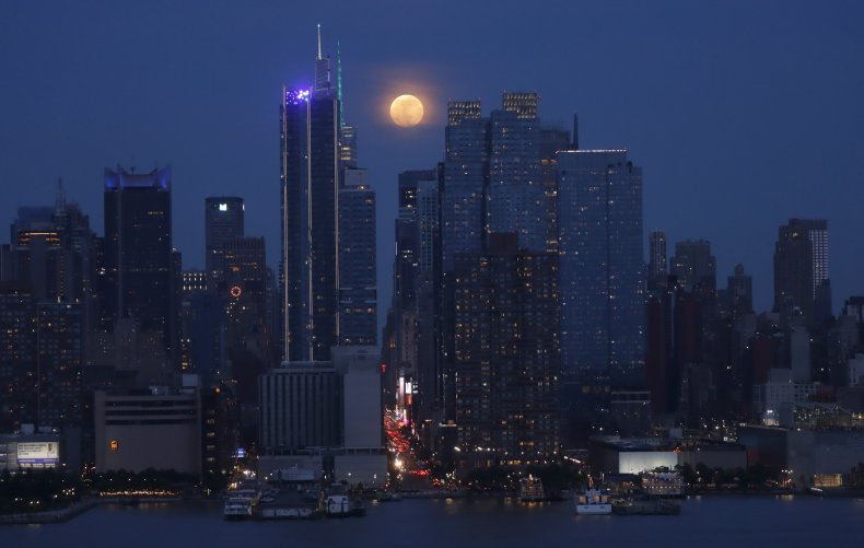 The full moon rises behind Manhattan