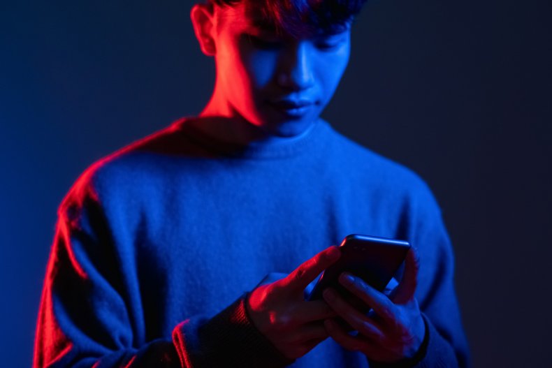 Man looking at phone in dark lighting.