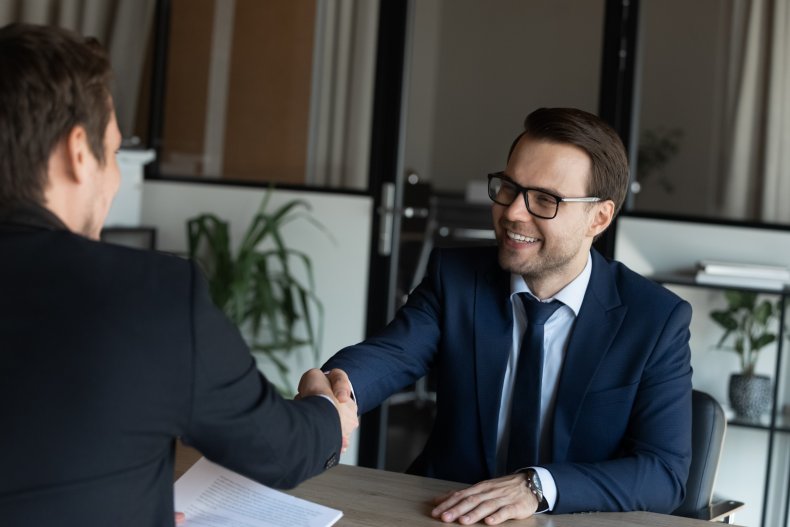 Two men shaking hands and smiling.