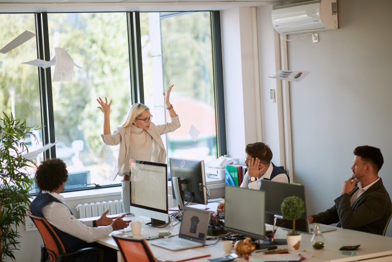Woman with hands raised in office setting.
