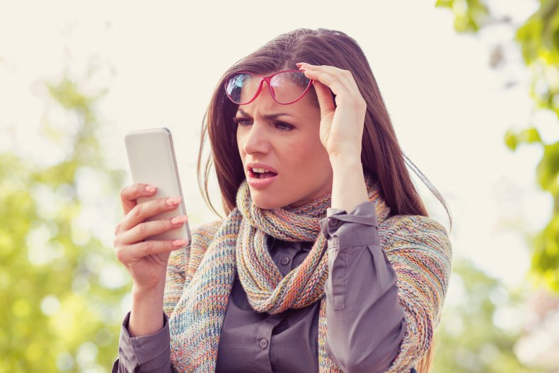 Woman looking at phone in disbelief