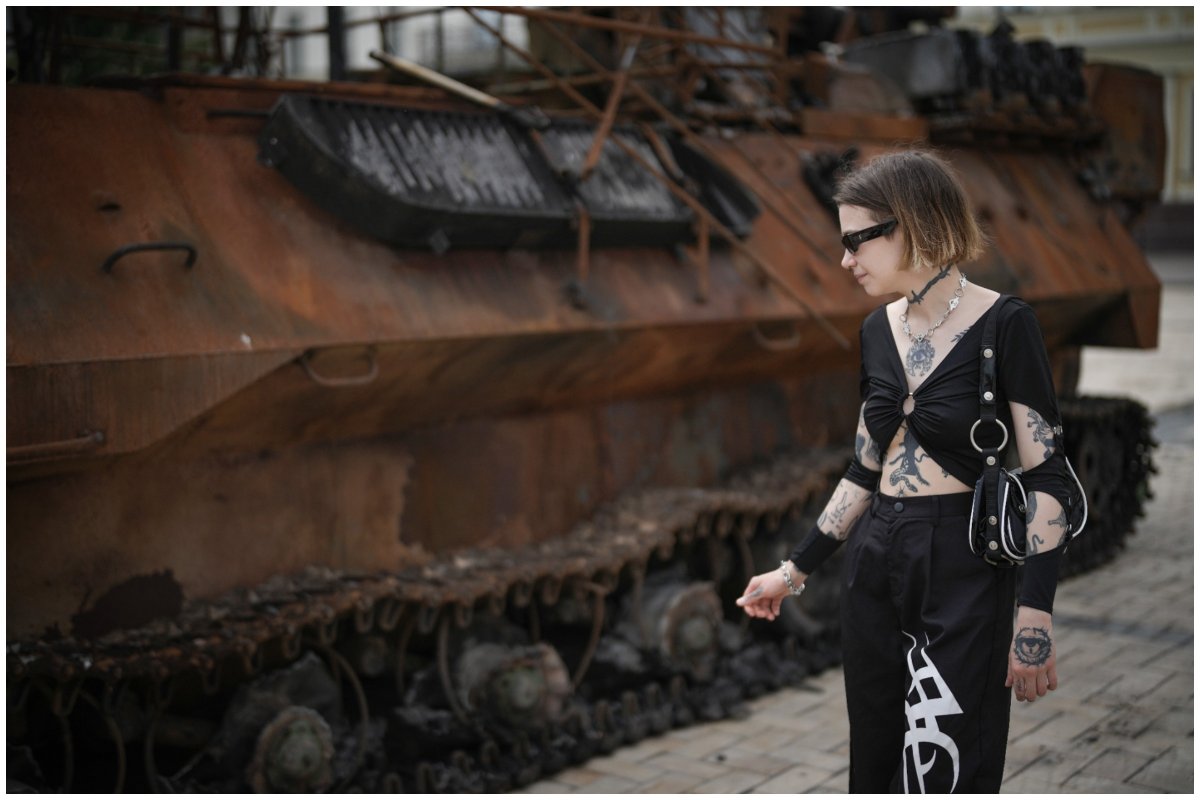 Woman standing next to destroyed tank