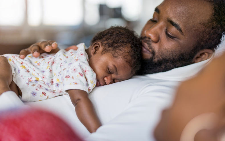 A dad with his sleeping baby.