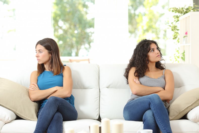 Upset sisters sitting on couch apart