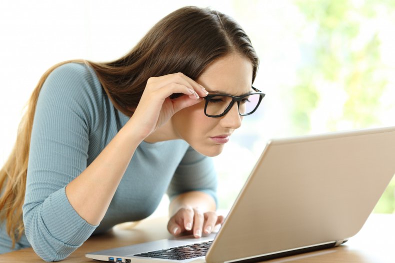 Woman looking at laptop while squinting