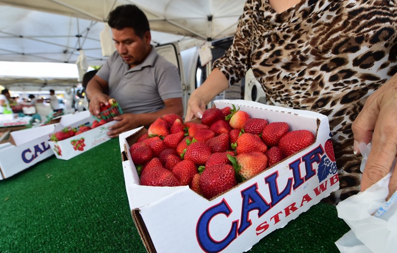 A person holding a box of strawberries.