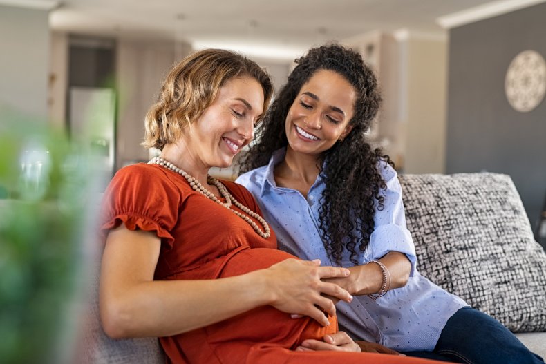 Two women with hands on baby bump.