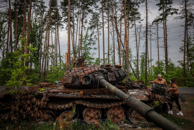 Local residents examine a destroyed Russian tank
