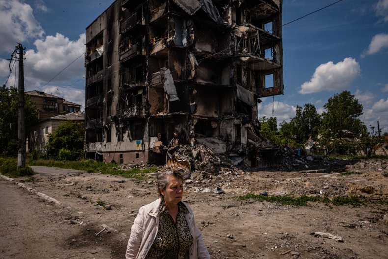A woman walks past a destroyed building