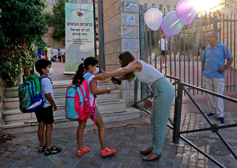 An Israeli teacher welcomes pupils wearing protective