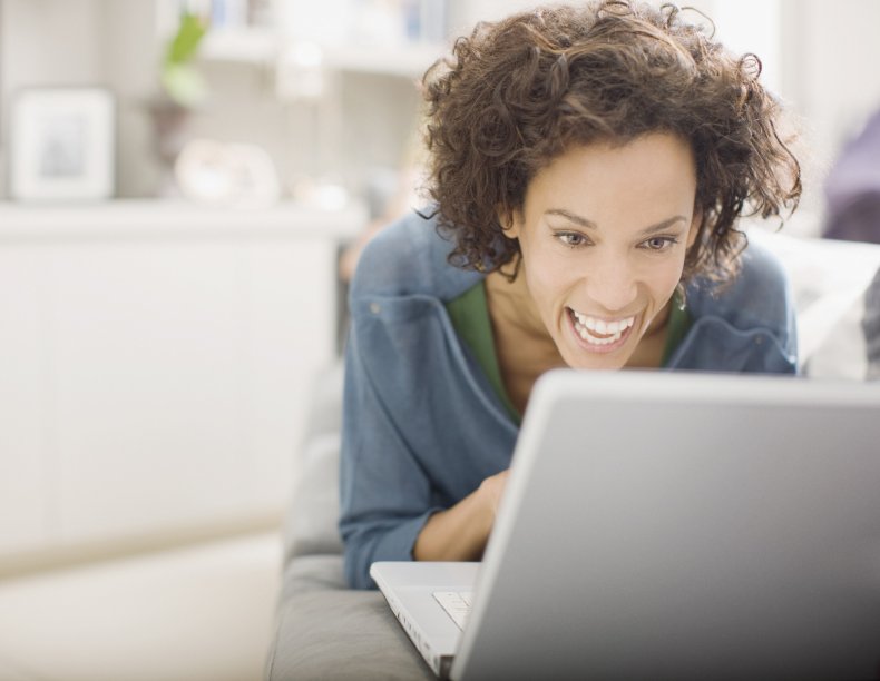 Woman laughing while looking at laptop
