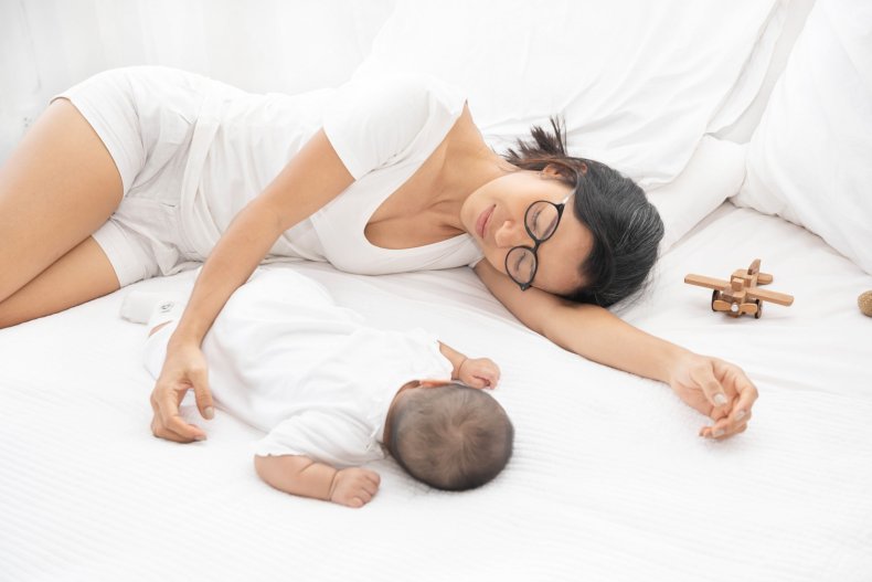 A tired mother sleeping next to baby.