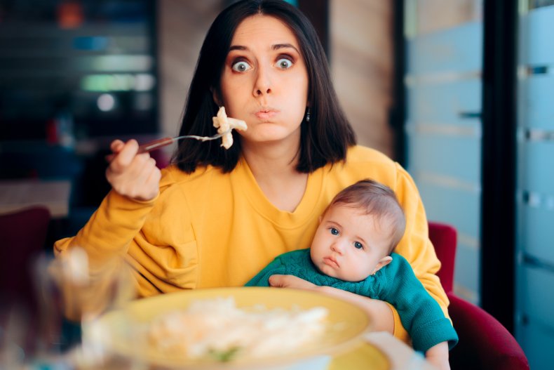 A mom eating while holding baby.