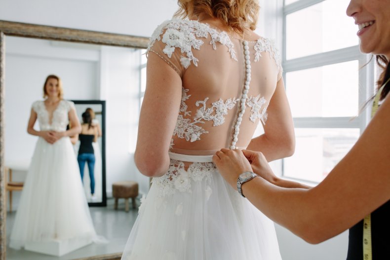 Person helping woman put on wedding dress