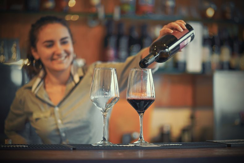 Bartenderen skænker vin i glas.