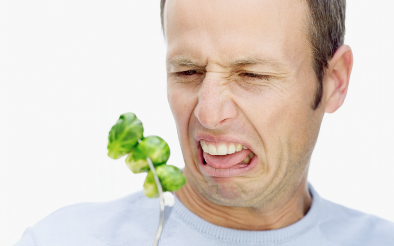 A man grimacing at some sprouts.