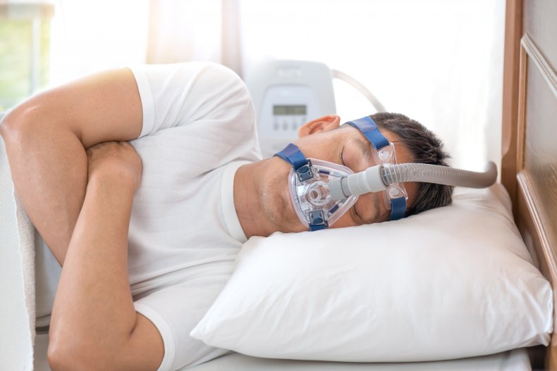 The man is sleeping with a CPAP machine