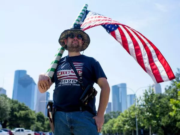 A typical middle-aged male Texan waving the America flag with his fat gut hanging out 
