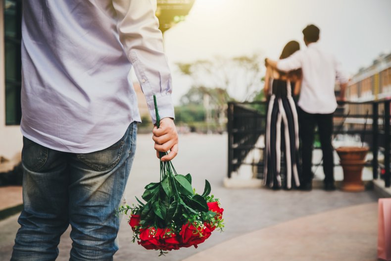 Man with flowers walks up to couple