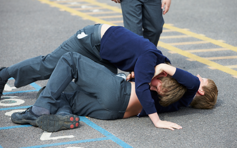 Two boys fighting in a playground.