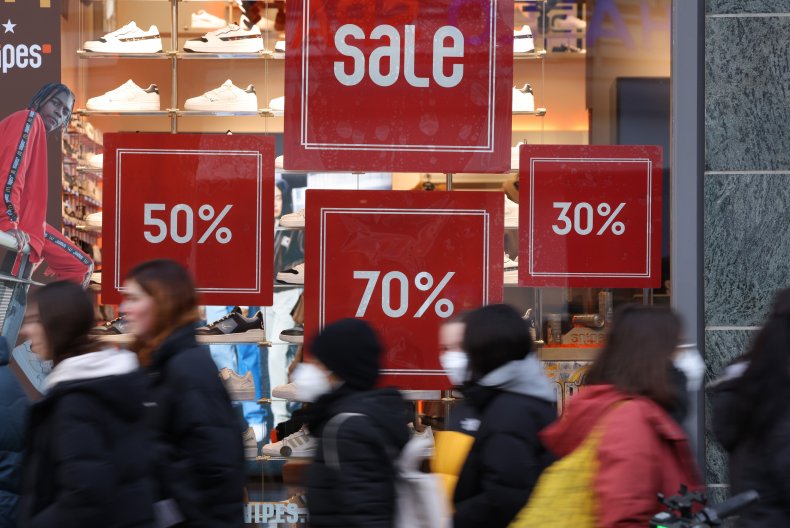 Shoppers walk past a store advertising sales 