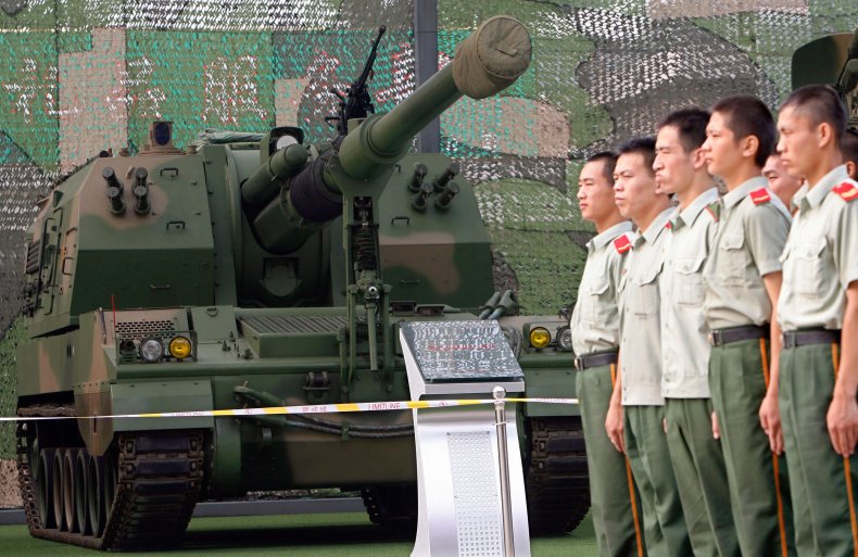 Chinese soldiers stand near a tank