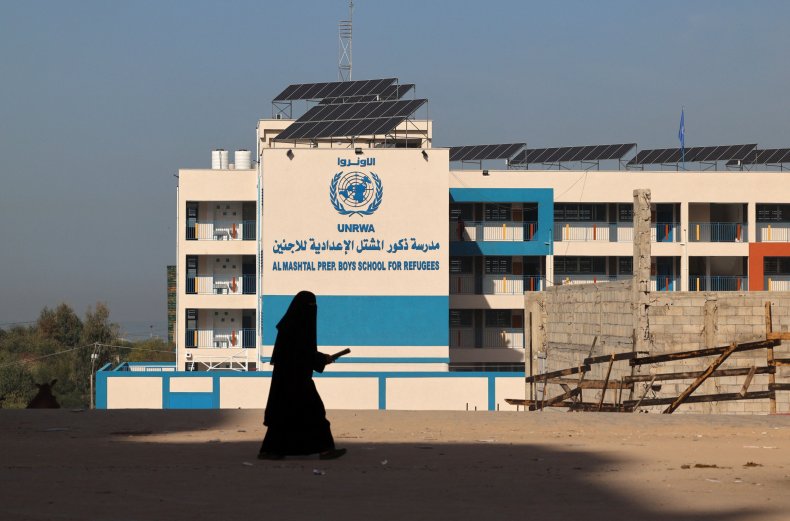 A Palestinian woman walks past the shuttered