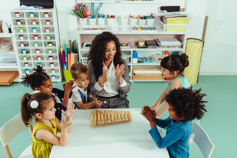 A preschool teach with students in classroom.