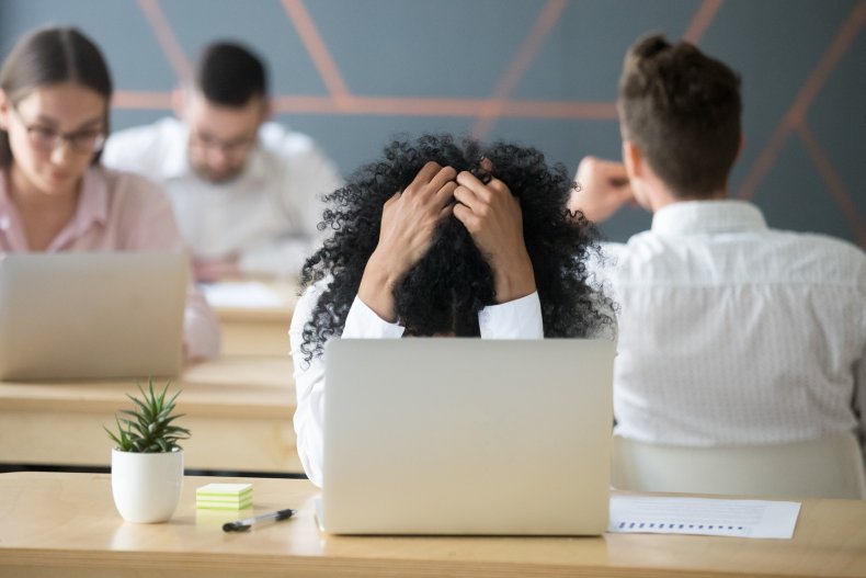 Woman with hands on head at desk.