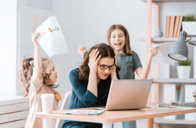 Woman looking at laptop, distracted by kids.
