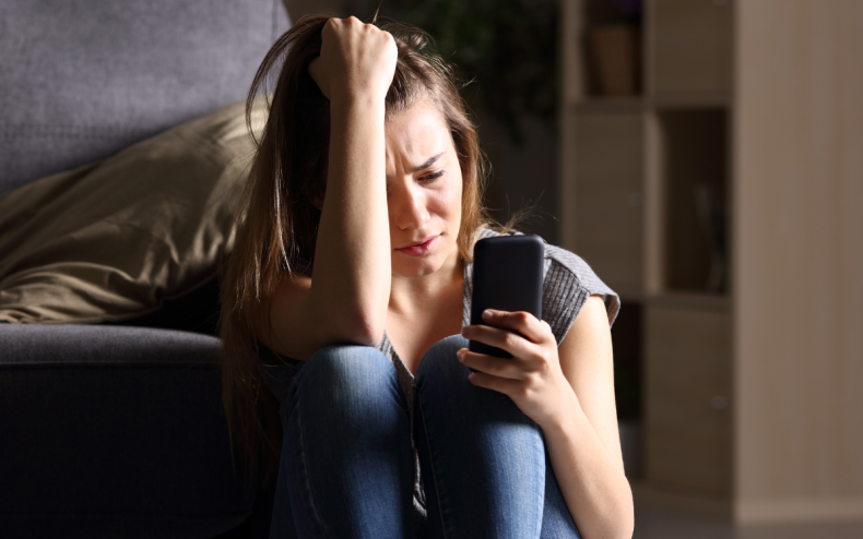 A woman upset looking at a phone.