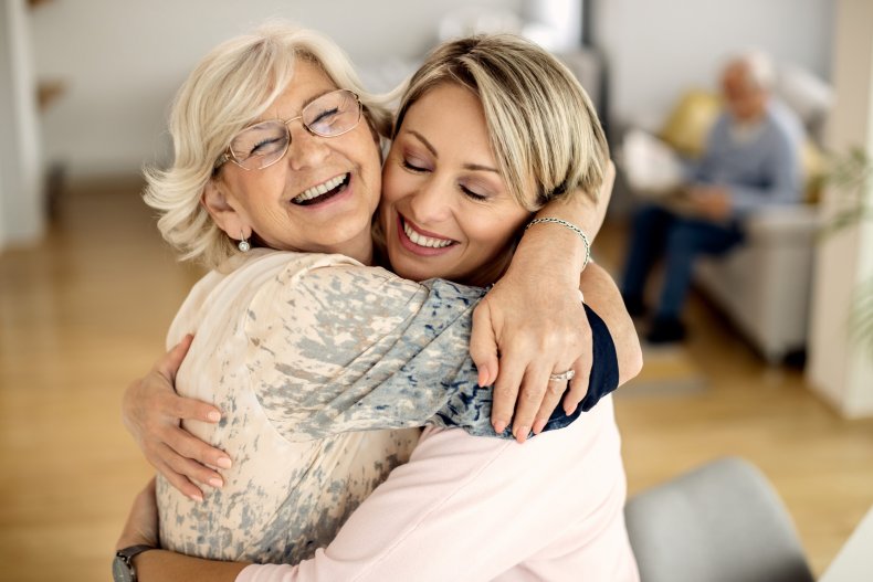 A mother embracing daughter and smiling.