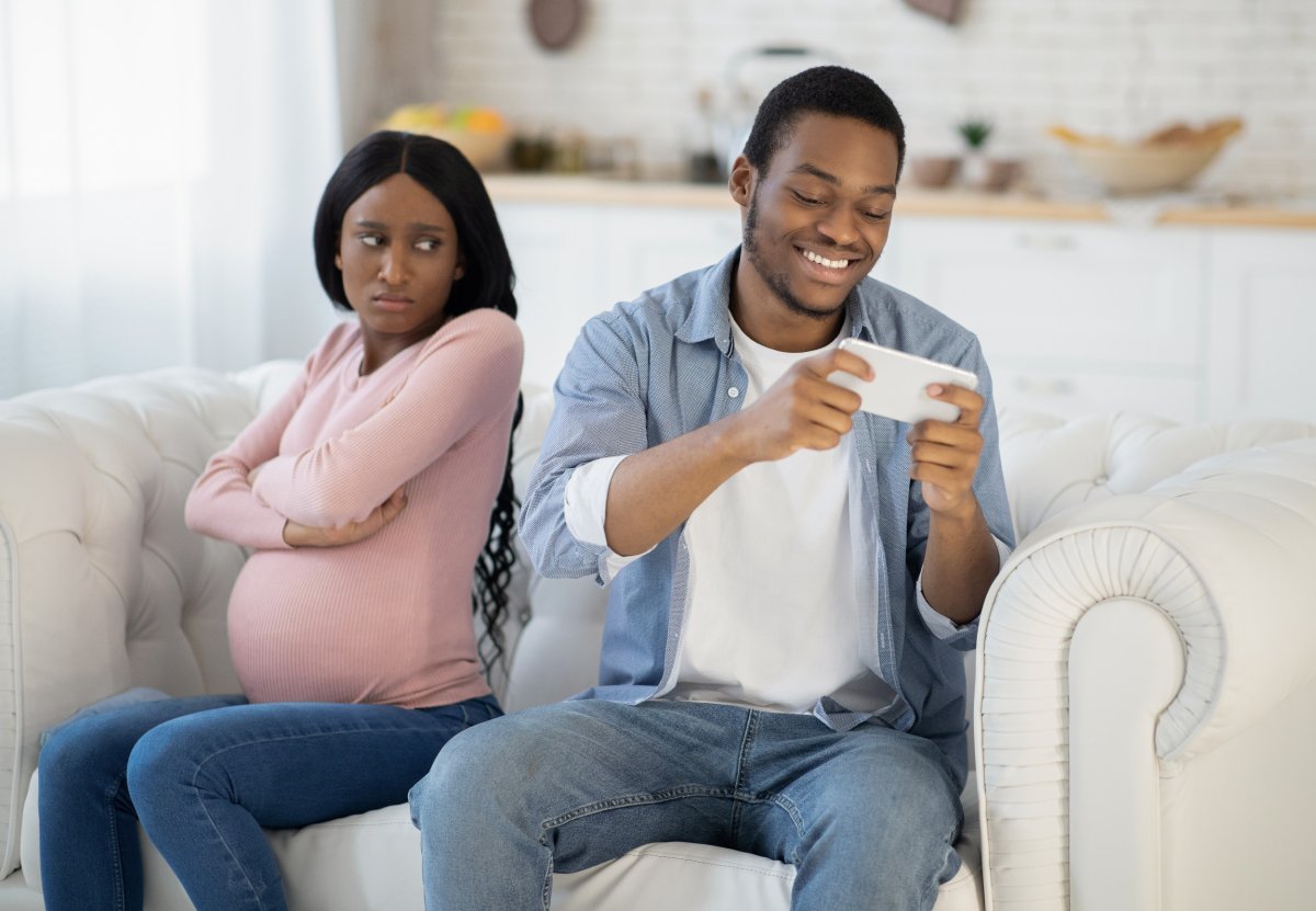 Pregnant woman next to man on cellphone.