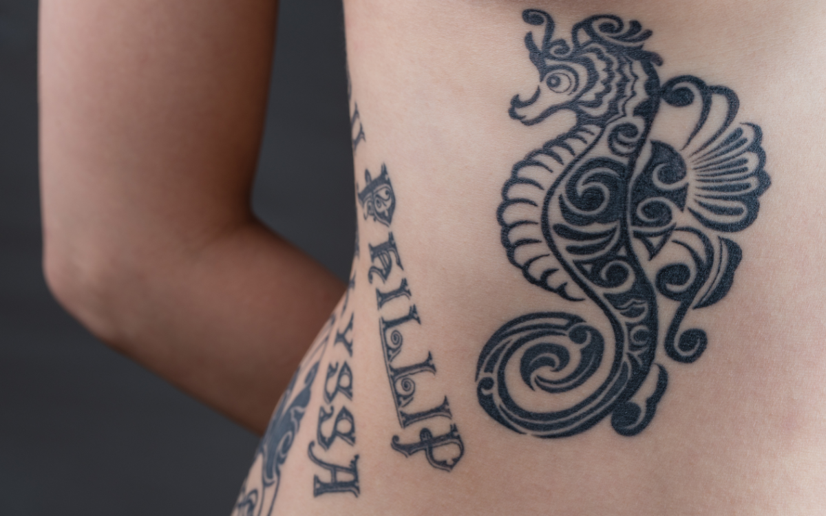 Tattoo Black Tribal Style Seahorse Children's Names Wrapping Woman's Ribs  Stock Photo by ©YAYImages 257816850