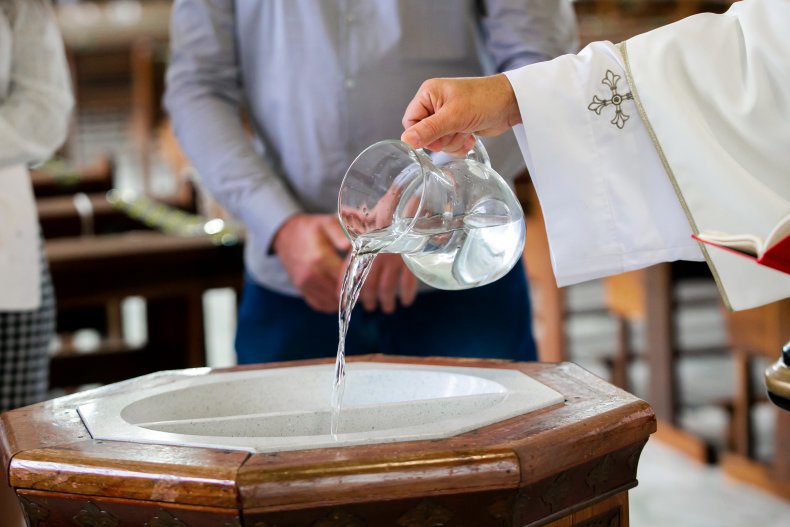 Priest pouring water in baptismal font
