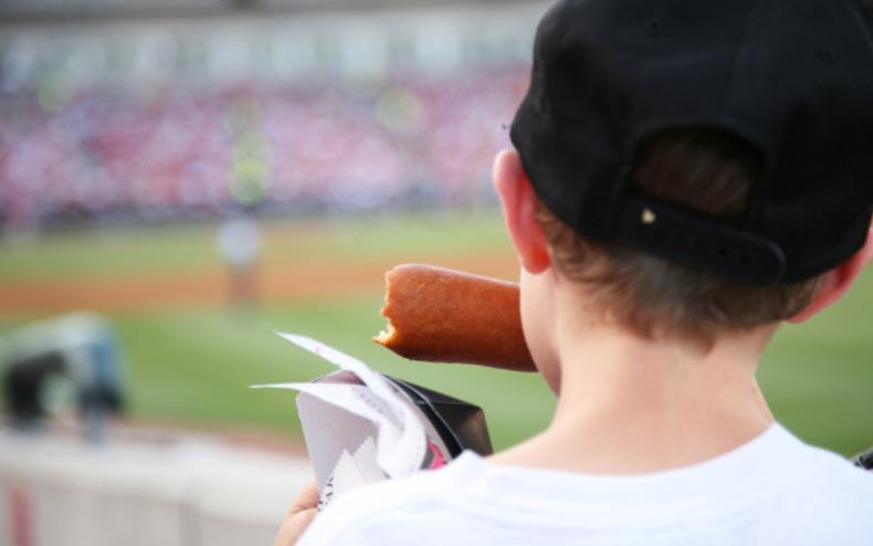 A baseball fan eating a hot dog.