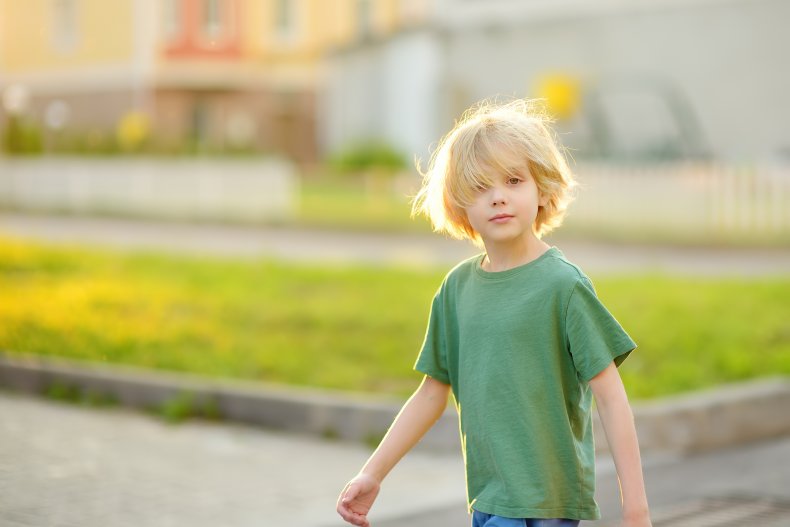 A young boy walking outdoors alone. 